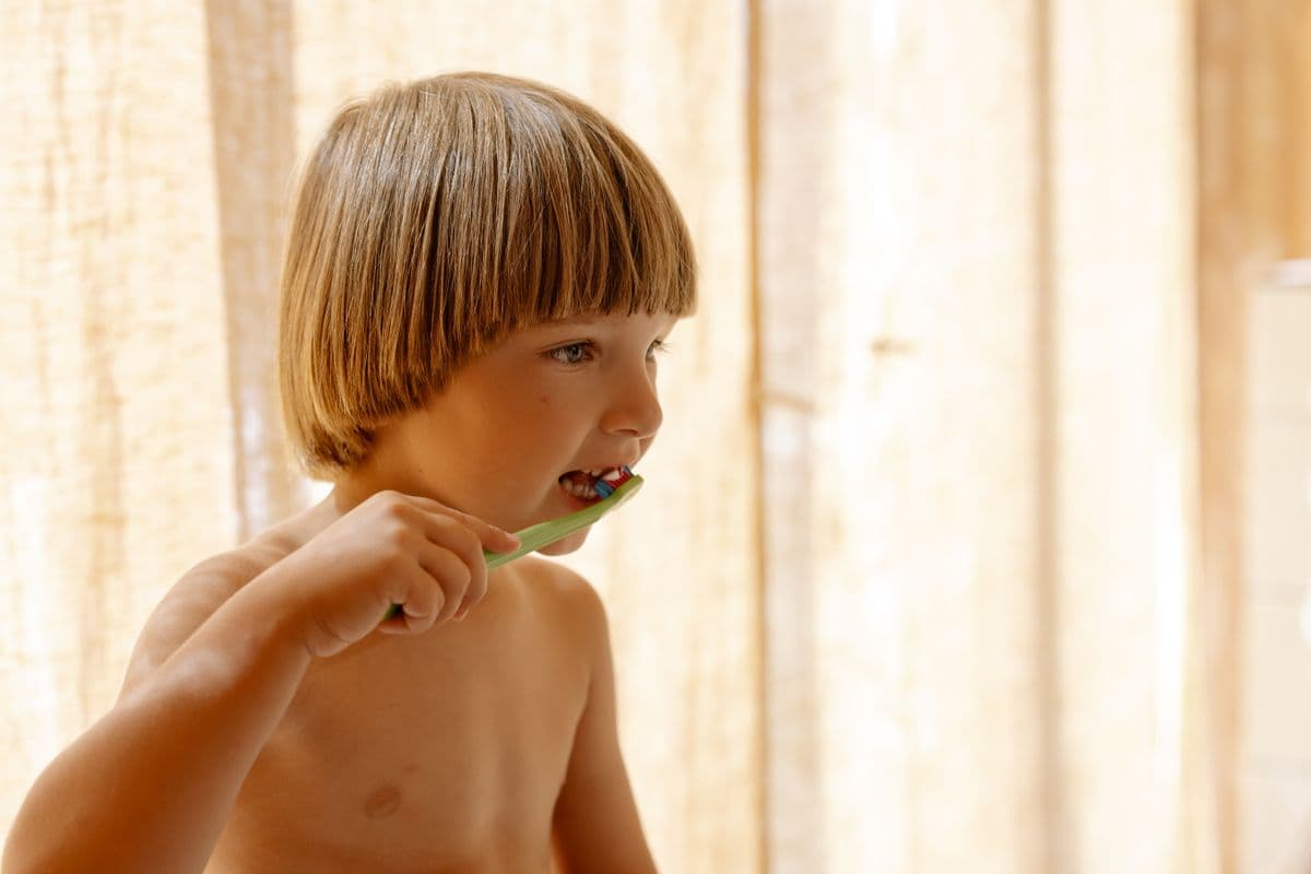A child brushing their teeth in soft natural light