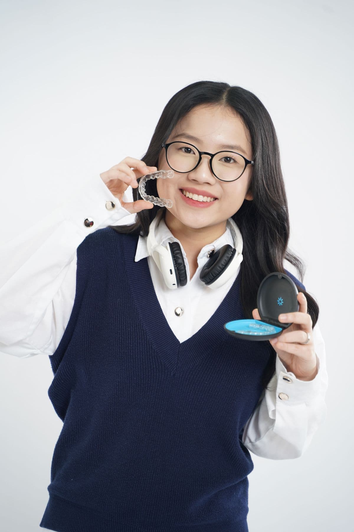 A person holding a clear aligner tray and its case